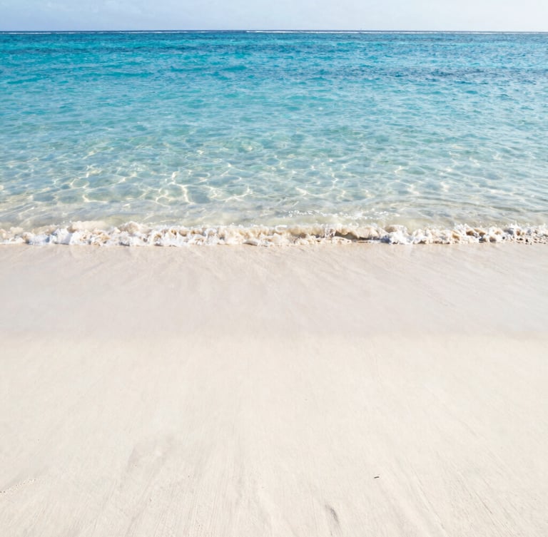 Pristine empty tropical beach with soft white sand and crystal clear ocean water, low horizon, wide environmental shot, golden-hour sunlight, peaceful and silent