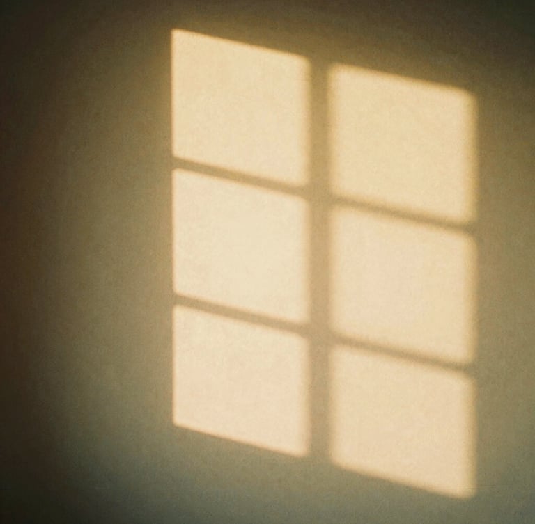 Soft diffused golden hour light shining through a window casting gentle shadows on a warm plaster wall, minimalist aesthetic, warm editorial photography, 35mm film