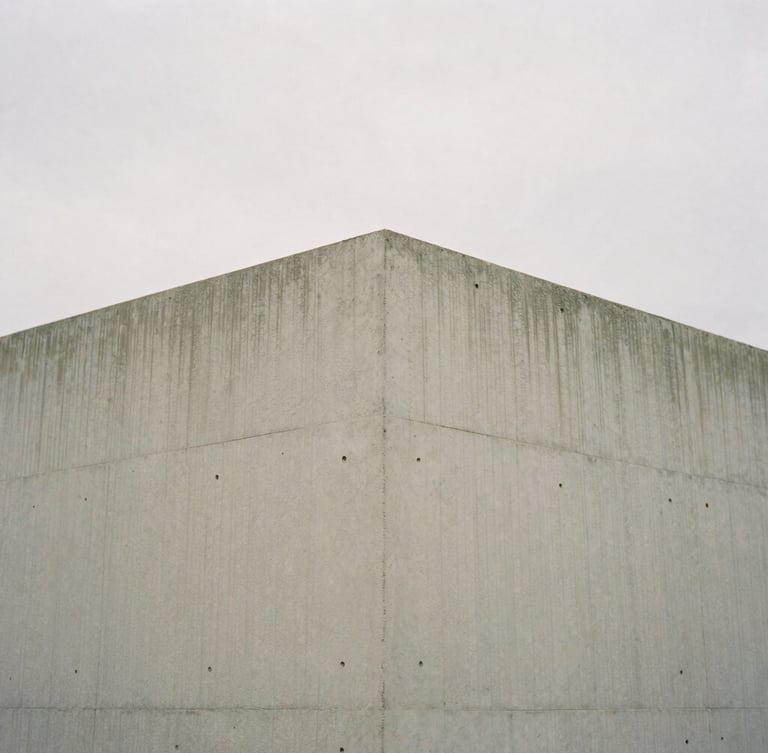 Minimalist editorial photography of a concrete architectural corner, soft diffused overcast daylight, muted natural tones, medium format film, quiet composition, 80mm.