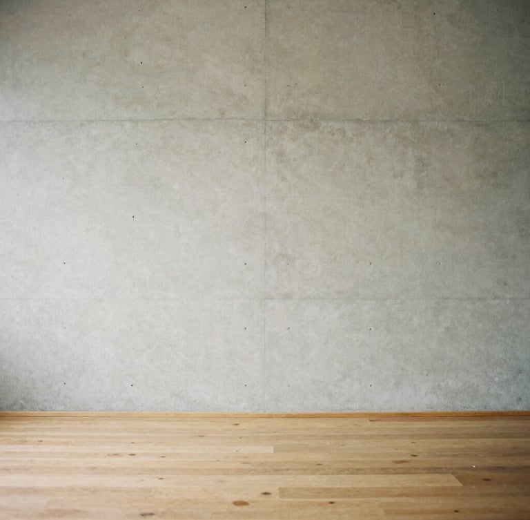 Minimalist concrete wall meeting a warm oak floor, soft diffused overcast daylight casting gentle shadows, medium format film aesthetic, 80mm.