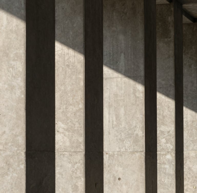 A vertical architectural crop of concrete columns casting sharp geometric shadows under diffused daylight.