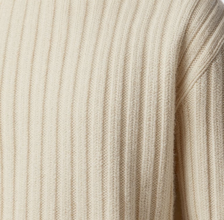 Extreme close-up macro shot of a cream-colored luxury wool sweater, showcasing intricate ribbed knit textures and fine-gauge yarn stitches under soft diffused studio lighting.