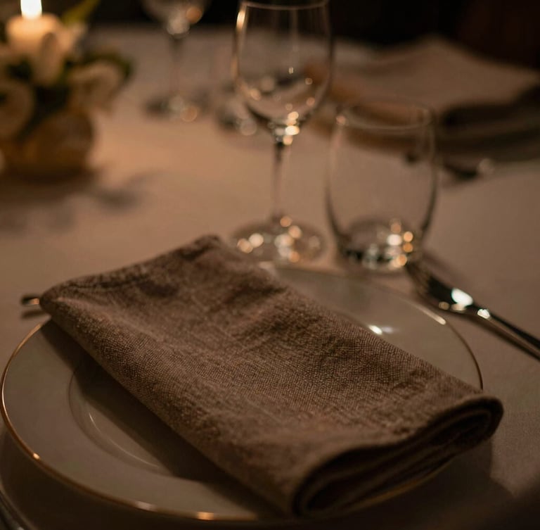 Close-up macro shot of premium textured linen and polished glassware on a corporate hospitality table, warm low-key lighting, shallow depth of field