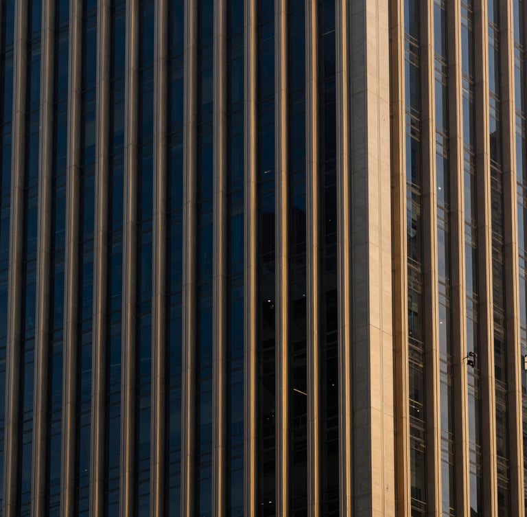 Architectural details of a modern financial skyscraper in Singapore, dramatic side-lighting, deep navy and warm brass tones, sharp focus, 35mm