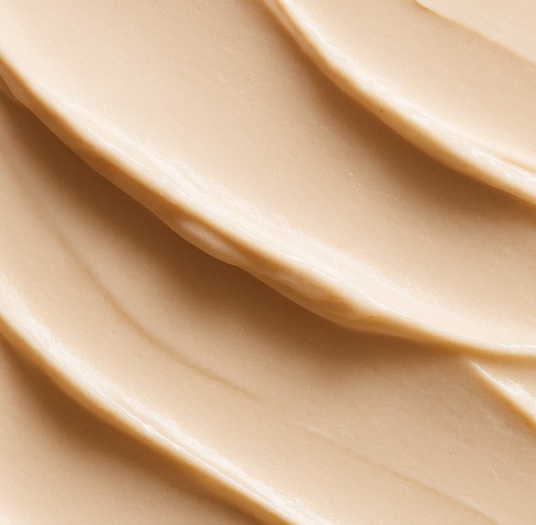 Macro beauty texture of a rich cream swatch with soft shadows, natural side-lighting, warm alabaster tones, minimalist elegant composition