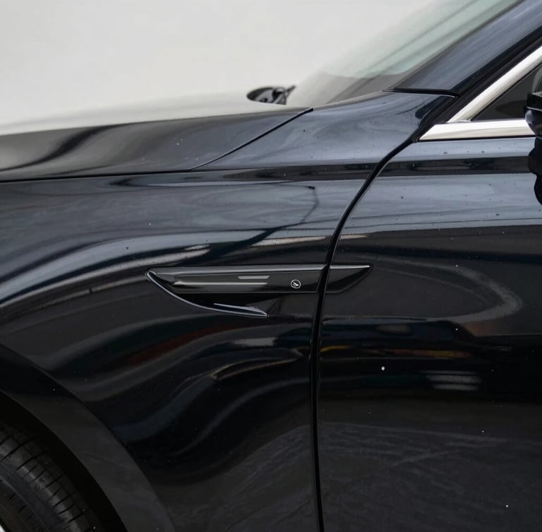 Macro shot of a freshly polished deep black car fender reflecting crisp architectural lines under soft studio light