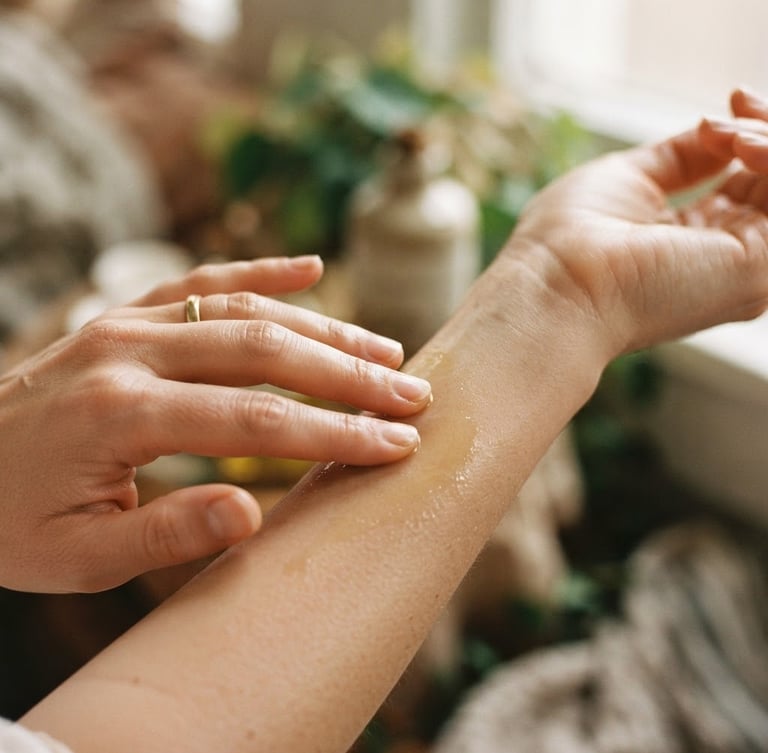 Close-up of hands gently applying botanical oils to skin, soft diffused warm daylight, shallow depth of field, natural textures.