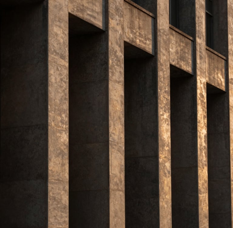 A close-up of a finished institutional concrete facade with sharp shadows cast by dramatic afternoon sunlight, warm bronze tones, 35mm