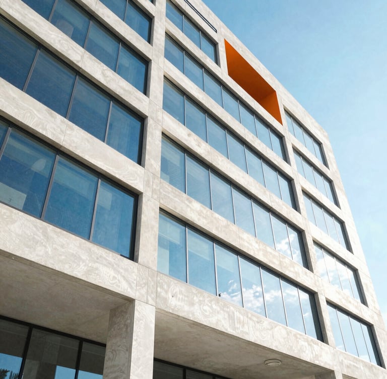 Wide-angle architectural crop of a modern concrete and glass building facade in Tampa under bright high-key natural daylight, sharp shadows, electric blue sky reflection