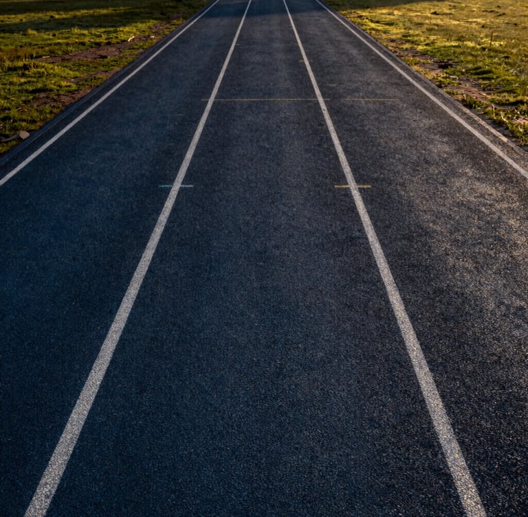 Wide environmental shot of a completed premium athletic track in India, dramatic natural sunlight, high-contrast deep tones, professional sports editorial photography, sharp focus, 35mm lens