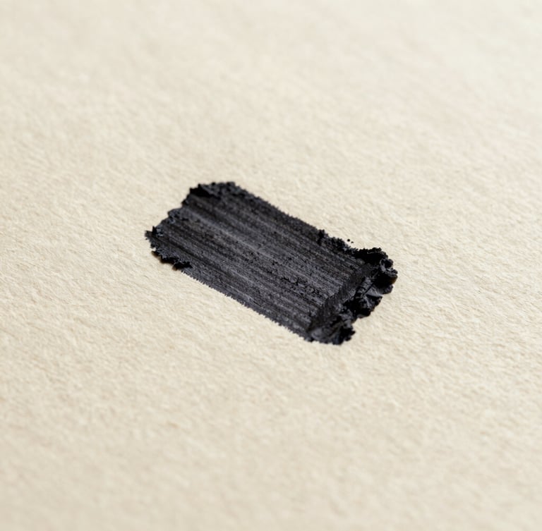 Extreme close-up macro shot of deep black ink pressed onto heavily textured uncoated cream paper stock, soft natural side-light casting subtle paper grain shadows.