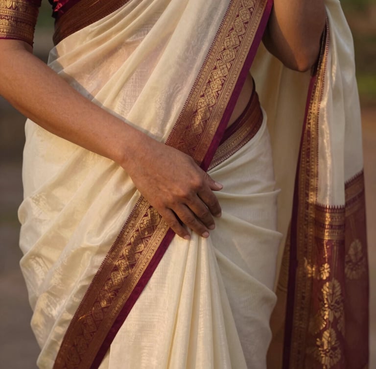 Close-up of a woman's hands gently draping a silk saree, light catching the intricate zari border, soft golden hour light, shallow depth of field, warm editorial photography