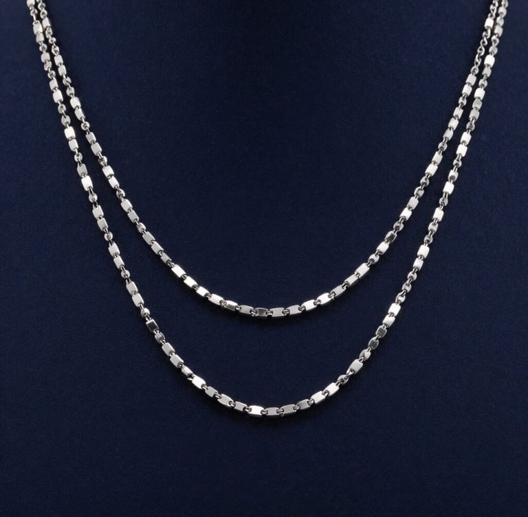 Macro photography of three layered silver necklaces on elegant neck, cool studio lighting, deep navy background, sharp metallic reflections.