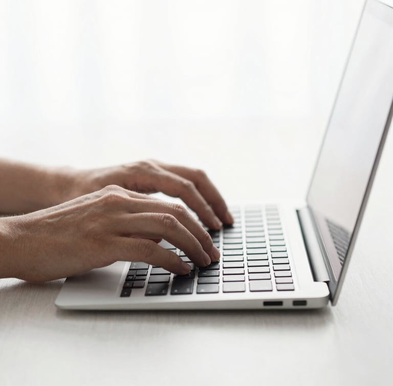 Close-up of hands typing on a sleek, minimalist keyboard, clean desk surface, soft natural light, cool gray tones, editorial composition
