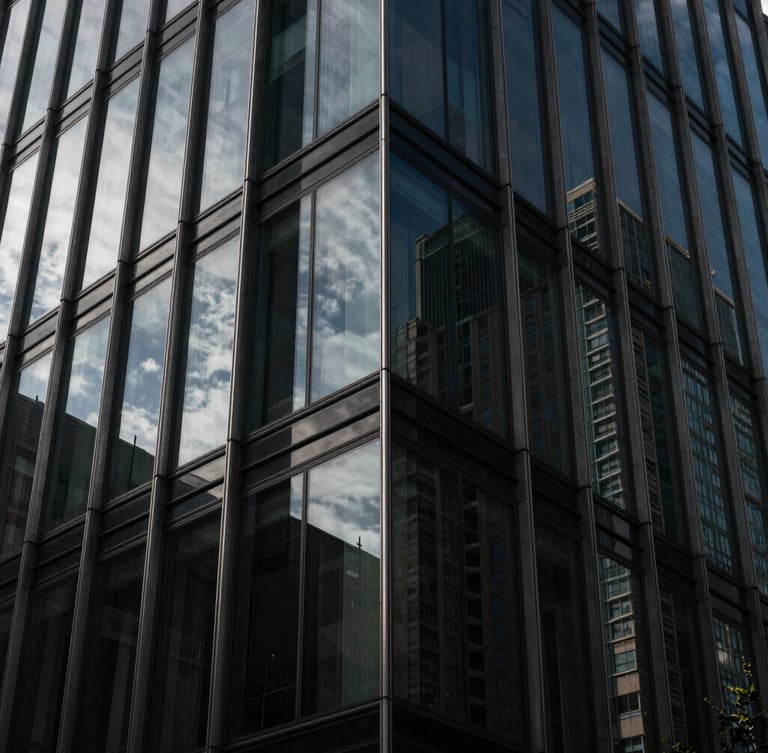 Severe architectural detail of a modern glass-and-steel skyscraper facade in Madrid, sharp geometric angles, dramatic chiaroscuro with deep shadows and cool daylight reflecting off the dark tinted glass, high-contrast luxury aesthetic.