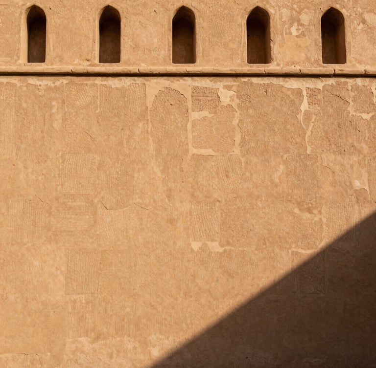 High-contrast architectural photograph of a restored Omani fortress wall, showing the seamless transition from ancient crumbling mudbrick to reinforced modern lime mortar
