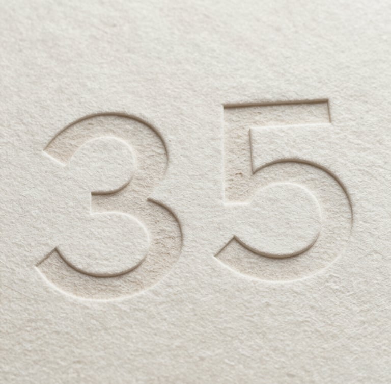 Extreme close-up of heavy cotton paper stock with deeply debossed minimalist typography, sharp geometric shadows, neutral studio light, 35mm