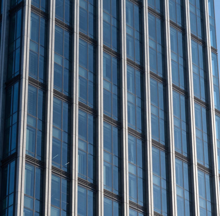 Crisp architectural photography of a modern glass and steel financial skyscraper facade, sharp high-contrast daylight with deep shadows, cobalt blue tones, 35mm
