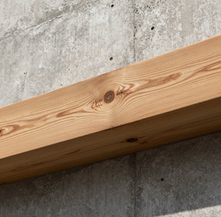 Tactile close-up of raw timber beams meeting a board-formed concrete wall, high-contrast side lighting, real shadows