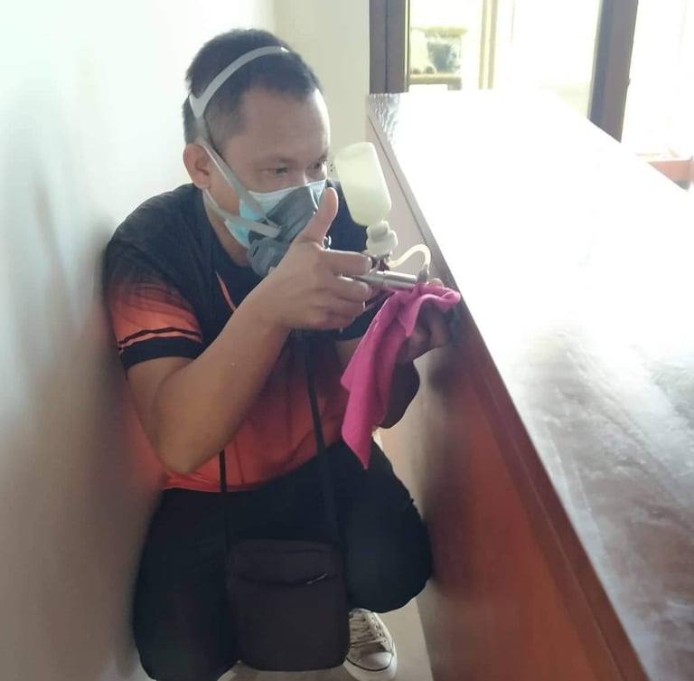 Professional exterminator wearing a mask and using a spray gun for indoor pest control treatment.
