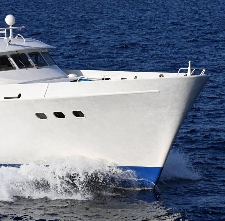 Dynamic low-angle shot of the bow of Aurora Fortunada cutting through deep blue water, crisp white hull, bright afternoon sun, water spraying from the hull.