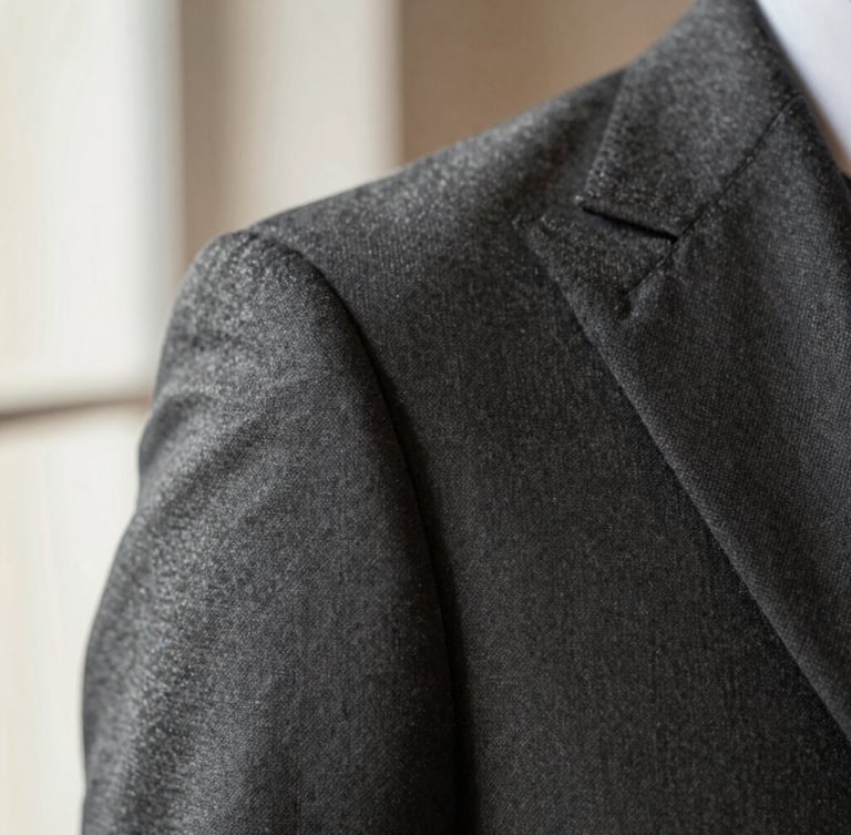 Macro photography of a structured suit shoulder seam, precise hand-finished stitching, premium wool fabric texture, warm gray lighting