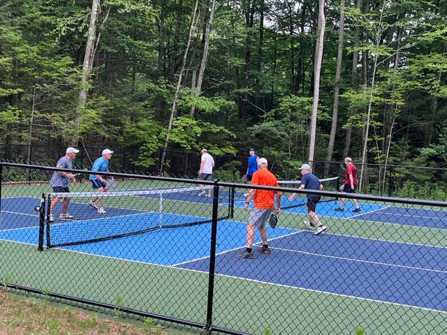 Men playing pickleball doubles on an outdoor blue and green pickleball court