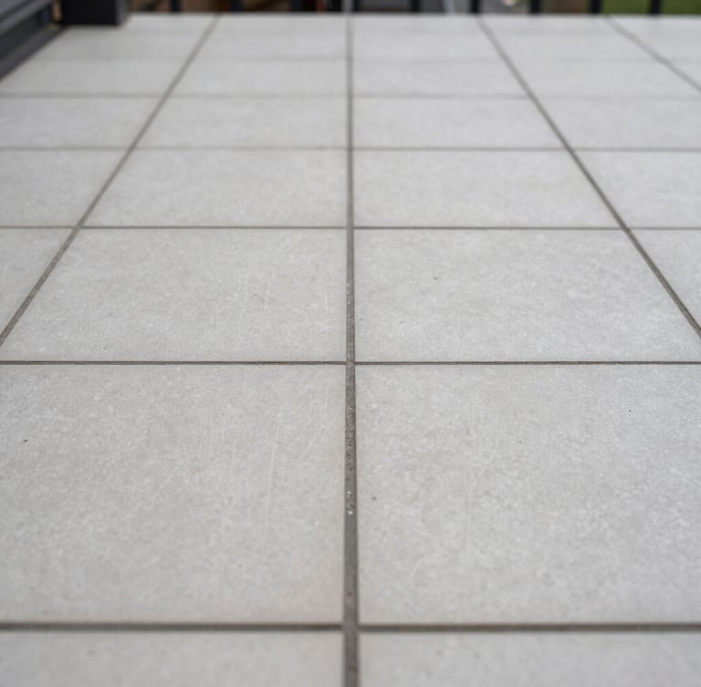 A crisp, close-up shot of perfectly aligned outdoor porcelain tiling joints on a Dublin patio, soft overcast Irish daylight, straight-on architectural lines showing structural precision.