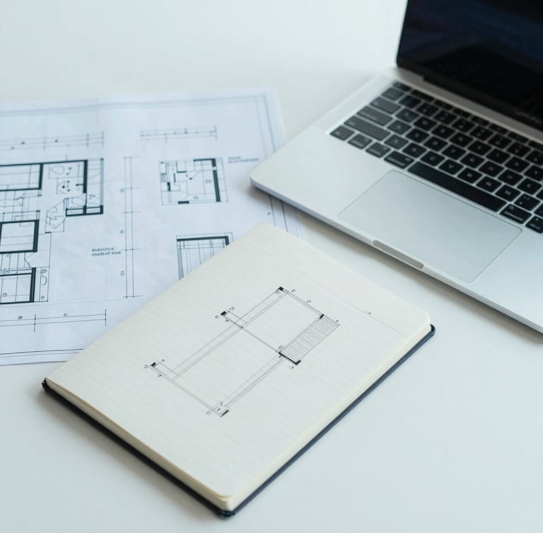 Overhead desk shot of a clean minimalist workspace. Technical blueprints, a sleek laptop, a notebook with structured architectural diagrams. Cool blue and teal lighting, sharp focus, professional editorial photography.