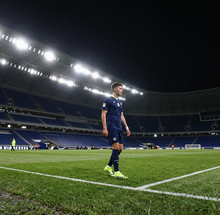 Wide dramatic stadium angle at night, football boots on wet turf under sharp spotlights, deep athletic navy tones.