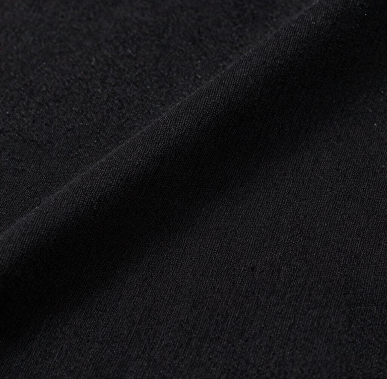 Minimalist studio macro shot of a Reserva black cotton t-shirt fabric texture, soft overhead lighting, sharp details