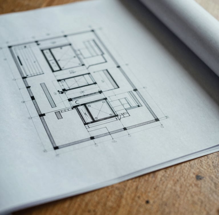 Close-up macro shot of architectural blueprints and industrial print materials on a solid oak table, cool overcast daylight, 35mm film.