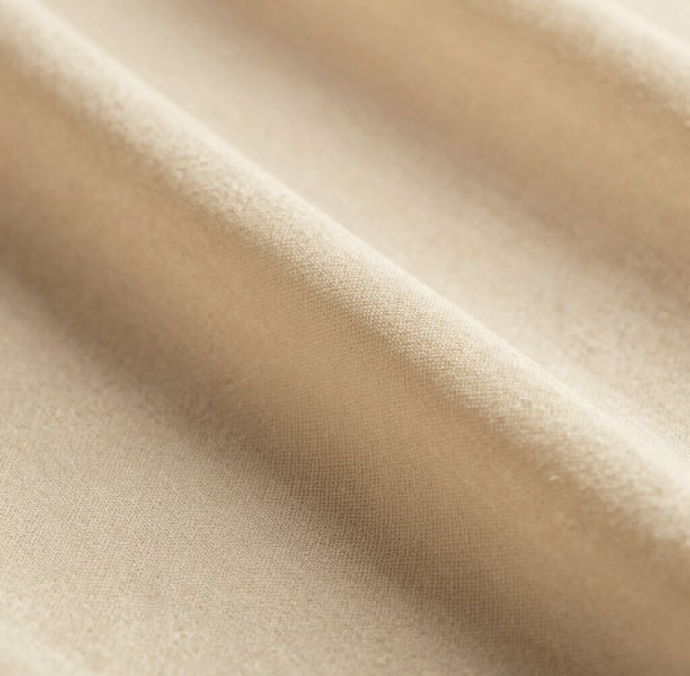 Extreme close-up of soft ivory cotton voile fabric texture, detailed weave, warm diffused light, shallow depth of field