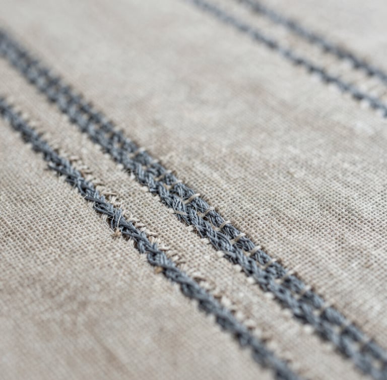 Detailed macro photography of historic silk tapestry weave under diffused natural side-lighting, muted linen and slate tones, shallow depth of field, 35mm