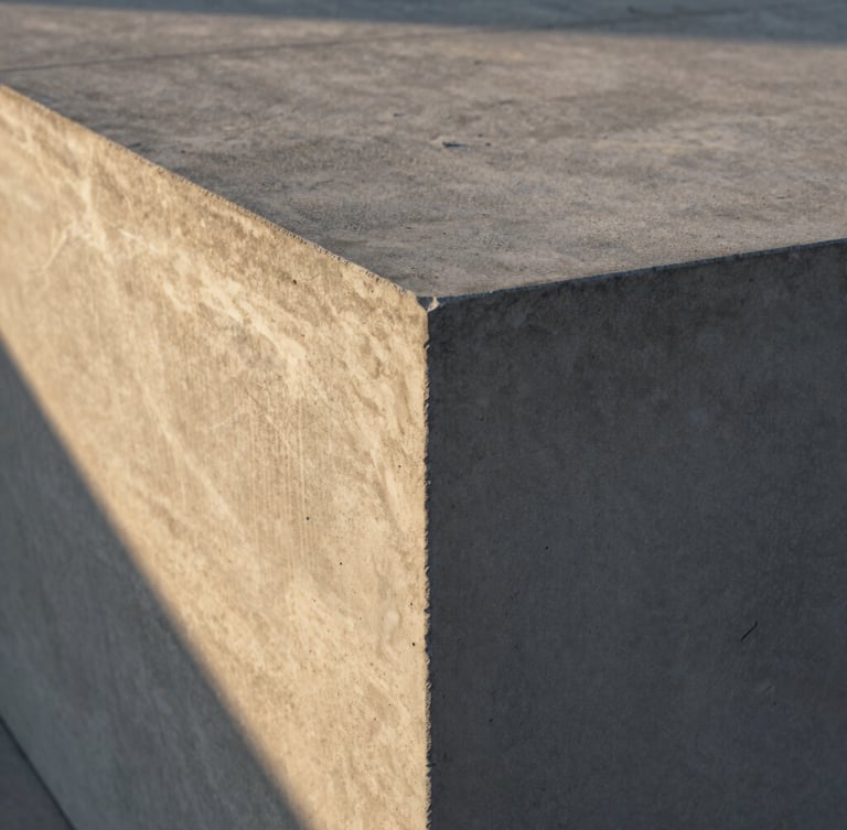 Close-up of finished textured concrete surface with crisp architectural edges, dramatic early morning golden hour light casting long shadows, 35mm.