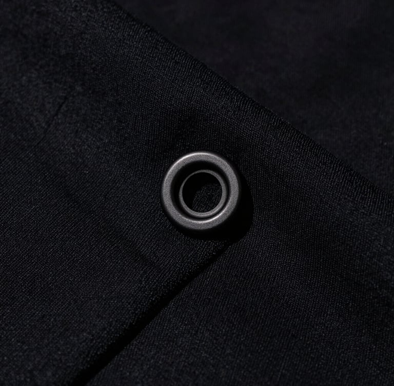 Extreme macro close-up of heavy-weight 400 GSM black cotton fabric texture, showcasing the dense weave and custom matte-black steel hardware under harsh direct studio light.
