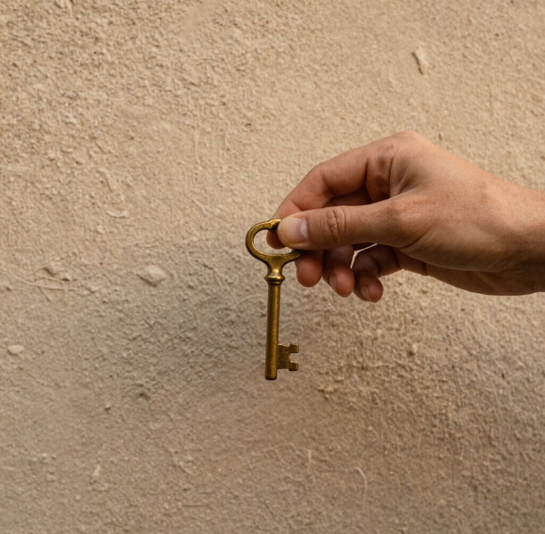 Close-up of a hand holding an old brass key against a textured plaster wall, soft morning light, warm earthy tones