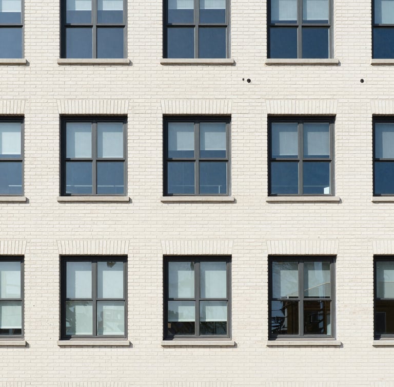 Architectural detail of a well-maintained commercial brick building exterior, clean windows, daylight, 35mm lens