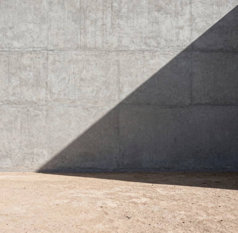 Stark architectural photography of a raw concrete wall casting a sharp geometric shadow across a dry desert floor, harsh direct sunlight, wide-angle lens