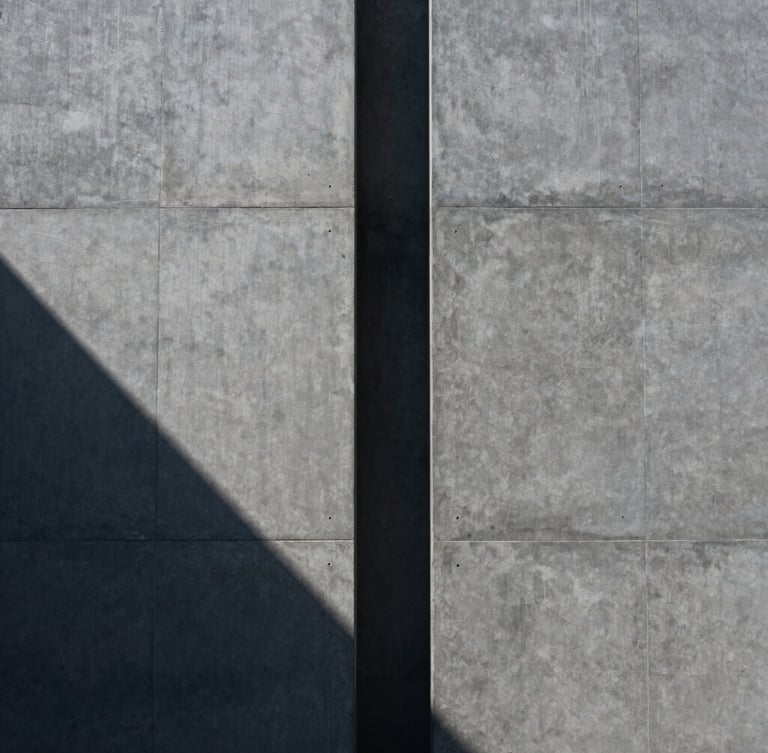 Symmetrical architectural concrete facade with sharp diagonal shadows, cool daylight, minimalist composition, 35mm lens