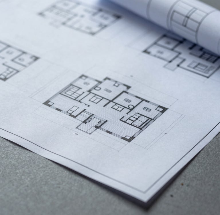 Macro close-up of physical architectural blueprints and digital wireframes on a slate gray desk, minimal shadows, clean studio lighting, cool overcast daylight, 35mm