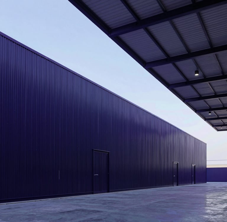 Wide-angle architectural shot of a modern clean warehouse interior in Muscat, cool-toned lighting with subtle purple and blue ambient accents, 35mm professional photography