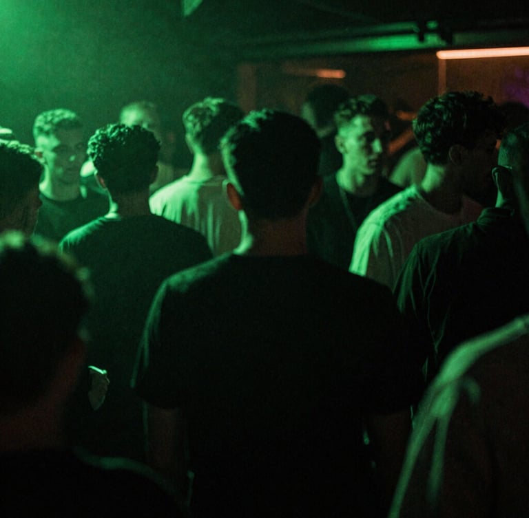 Gritty flash photography of a packed underground UK club dancefloor, high-contrast neon green ambient glow, deep shadows, 35mm film grain, motion blur.