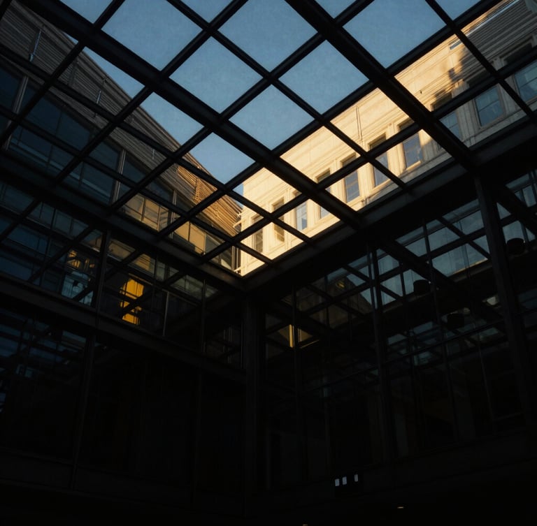 Dramatic architectural perspective looking up at a modern glass ceiling with golden hour reflections, low-key lighting, deep black shadows, 35mm