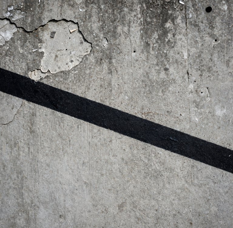 Extreme close-up of a raw, crumbling concrete wall in Chișinău, where a sharp, solid black painted line cuts across the textured decay under flat, overcast daylight.