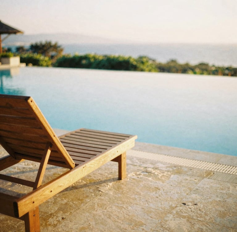 A sun-drenched quiet resort corner with a wooden lounge chair beside a calm turquoise pool, warm golden hour light, shallow depth of field, 35mm film