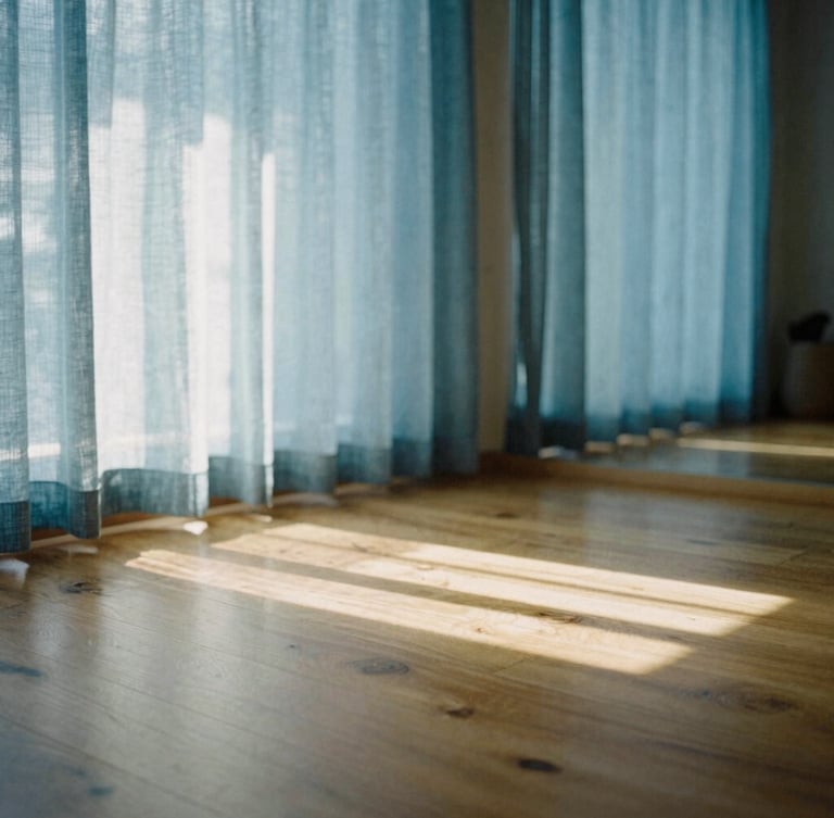 A quiet, sunlit yoga studio with natural wood floors and soft blue linen curtains, diffused morning light casting long shadows, serene film photography.