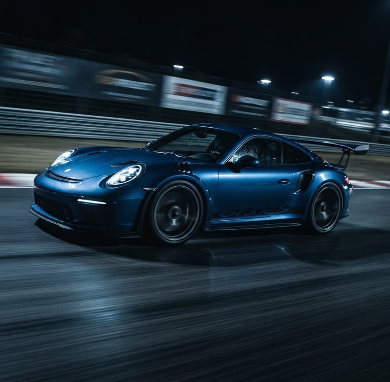 Low-angle dynamic shot of a modern sports car with motion blur on a dark track, dramatic blue studio rim lighting, cool dark tones, sharp detail, 50mm lens