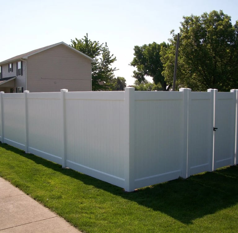 A clean white vinyl privacy fence with a matching gate installed in a residential backyard.