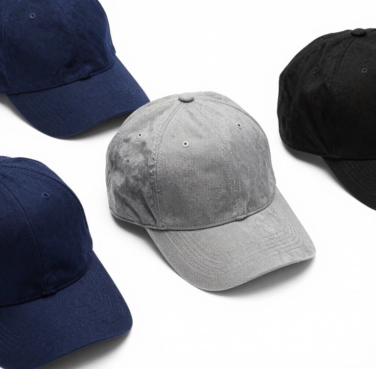 Symmetrical flat-lay of three premium branded corporate caps in navy, slate gray, and black, high-end retail photography, sharp focus